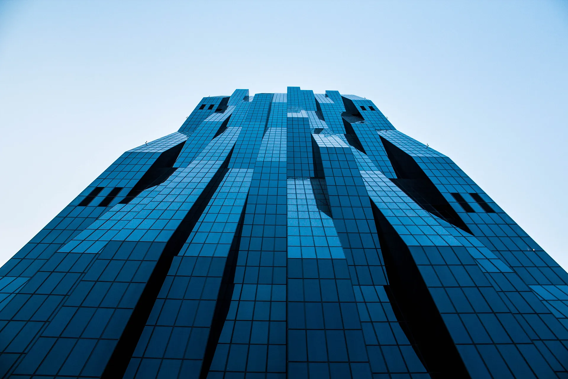 Ein beeindruckendes Hochhaus aus blauem Glas, fotografiert von unten.